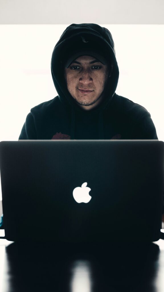 Person working on a MacBook Pro in a dimly lit room — focused creative environment