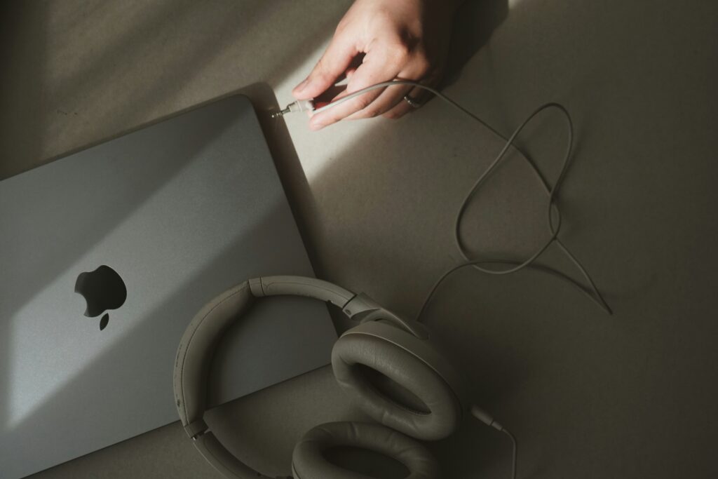 User connecting wired over-ear headphones to a MacBook – showcasing audio flexibility.