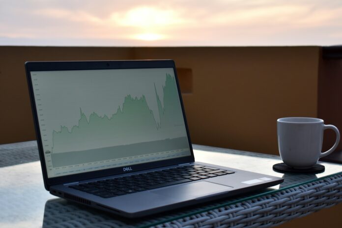 Dell XPS 16 laptop on outdoor table with graph analytics on screen at sunrise — remote productivity setup