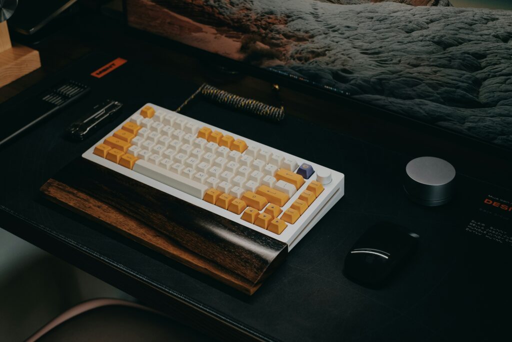 Custom mechanical keyboard and mouse on a clean desktop gaming setup with widescreen monitor
