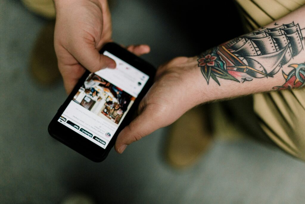 User browsing on a smartphone with tattoos visible on the forearm