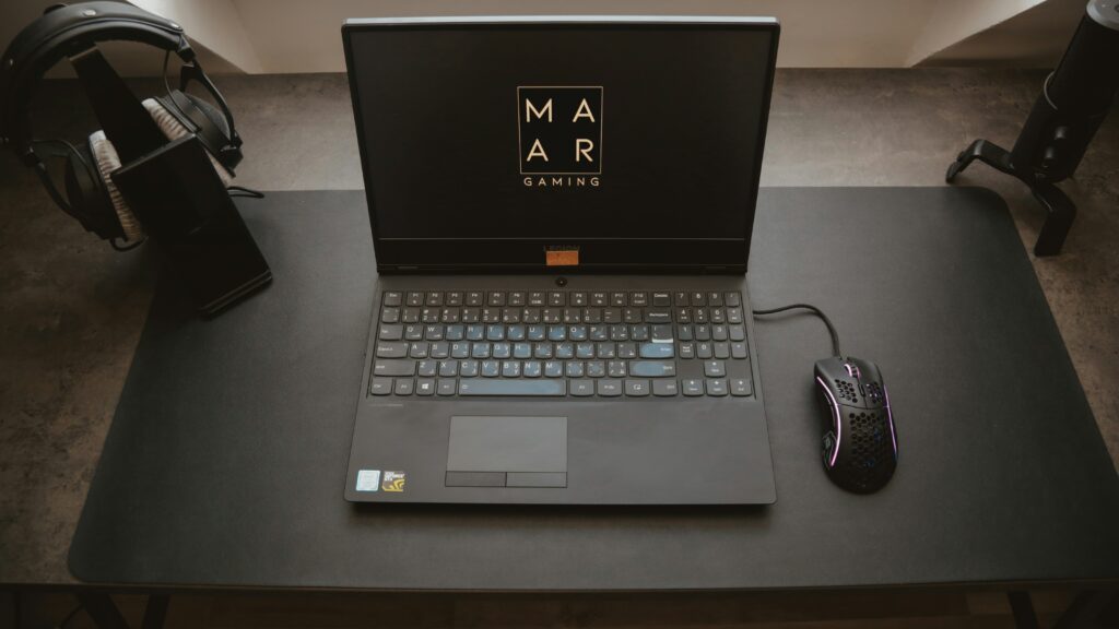 Minimal distraction-free work setup at home with gaming laptop and headphones on sleek black desk