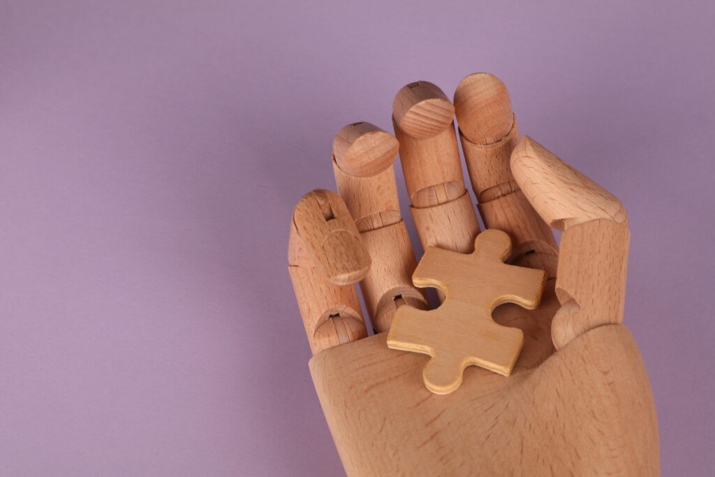 Symbolic wooden hand holding a puzzle piece to represent problem-solving with AI