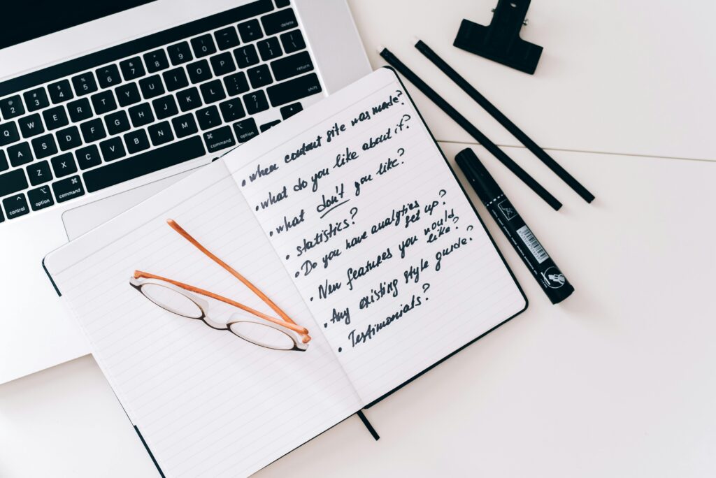 Creative brainstorming notes beside a laptop and reading glasses