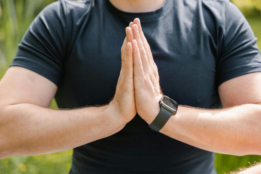 Man wearing a smartwatch while meditating outdoors — wellness and mindfulness tracking in 2025 wearables.