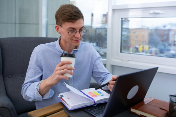 Young professional using AI tools for productivity while working remotely with a laptop and planner