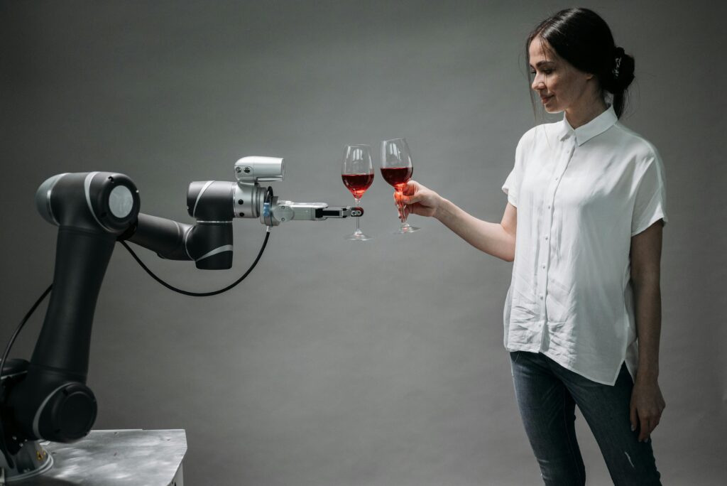 Woman toasting with a robotic arm in a symbolic moment of human-AI collaboration