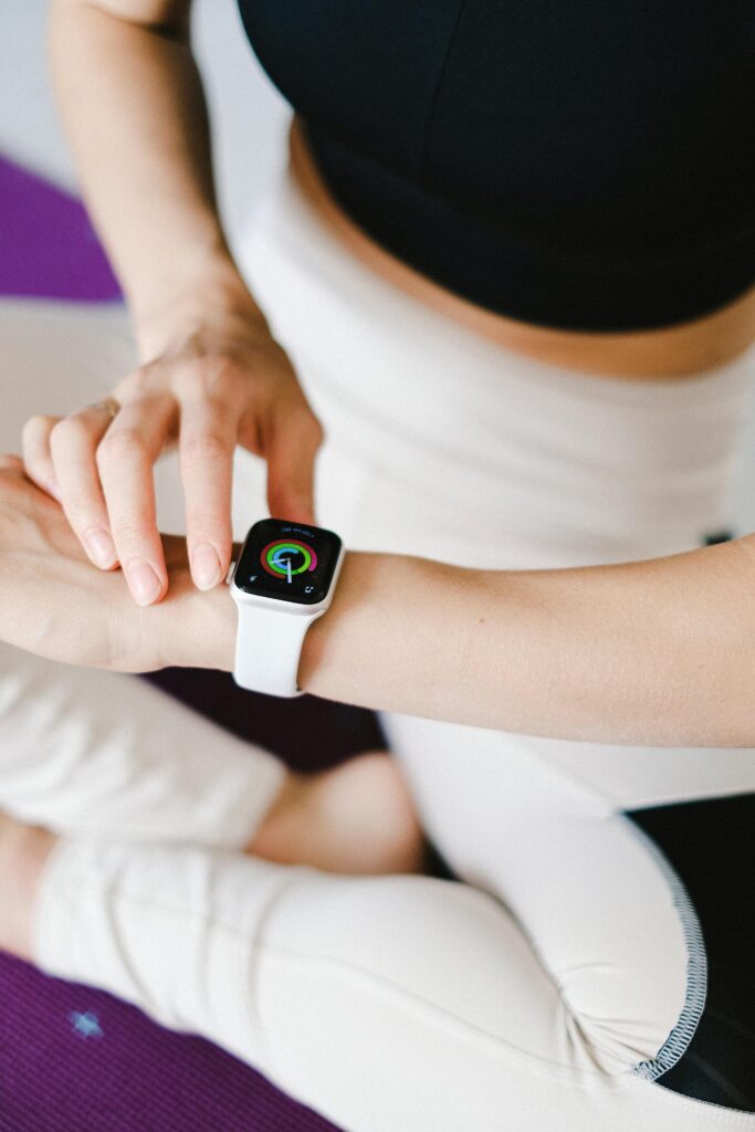 Woman checking her smartwatch rings during a yoga session — daily activity tracking feature of 2025 fitness wearables.