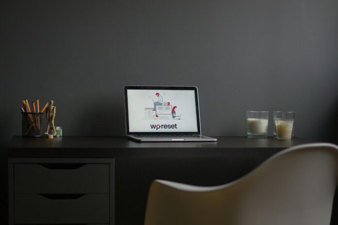 Minimal distraction-free work setup at home featuring a clean dark desk with a laptop and candles for a calming environment.