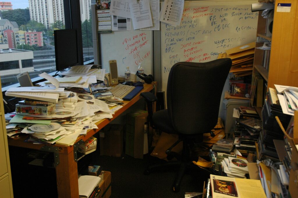 Cluttered office workspace showing the opposite of a minimal setup